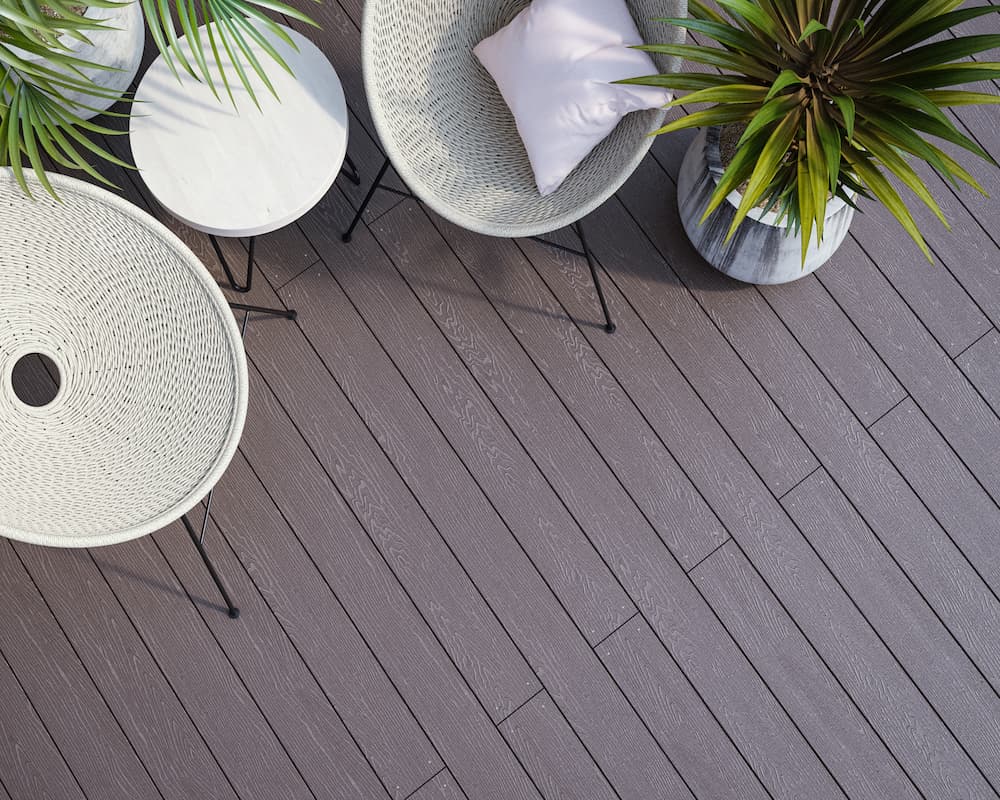 dark composite decking with 2 white chairs and plants